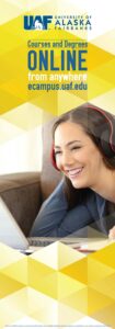 One side of a folding banner featuring a student wearing headphones and smiling while looking at a laptop